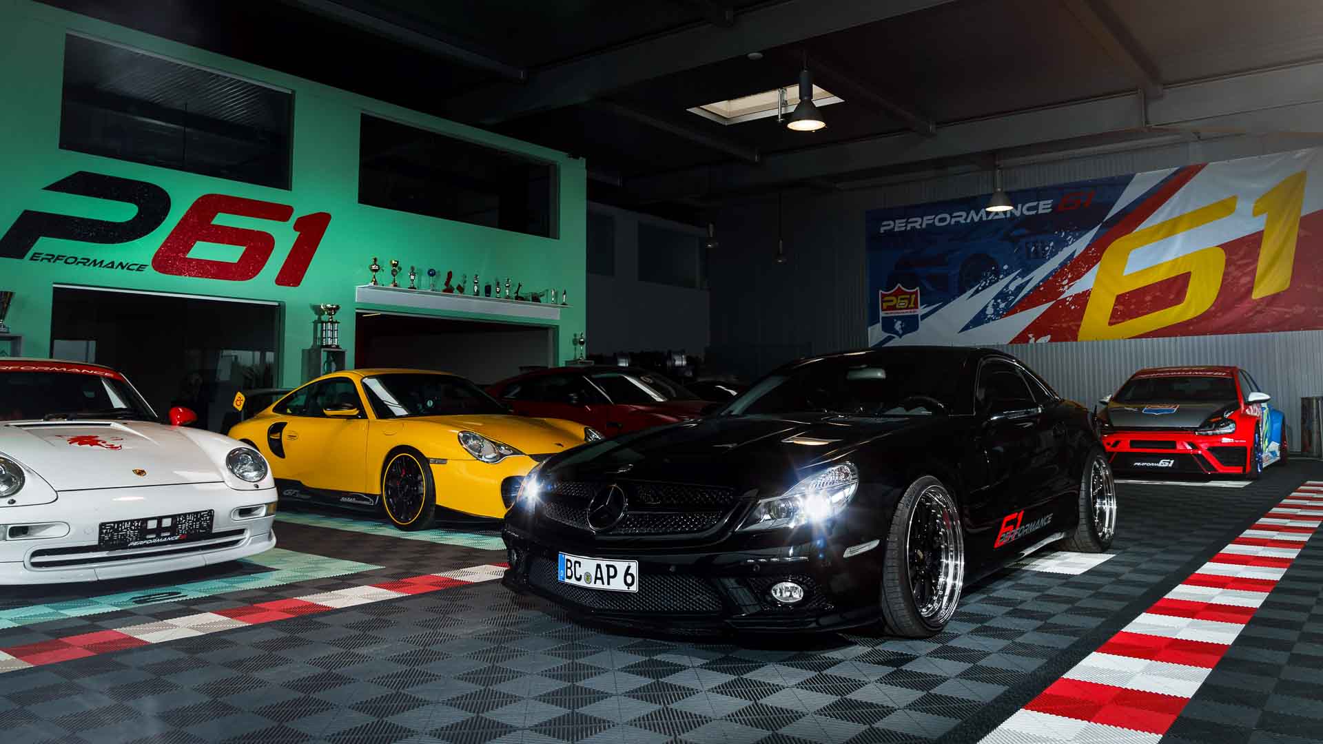 Showroom mit Sportwagen auf modular verlegten Klickfliesen in Schwarz, Grau und Rot – belastbarer Bodenbelag für Verkaufsflächen mit individueller Gestaltung.