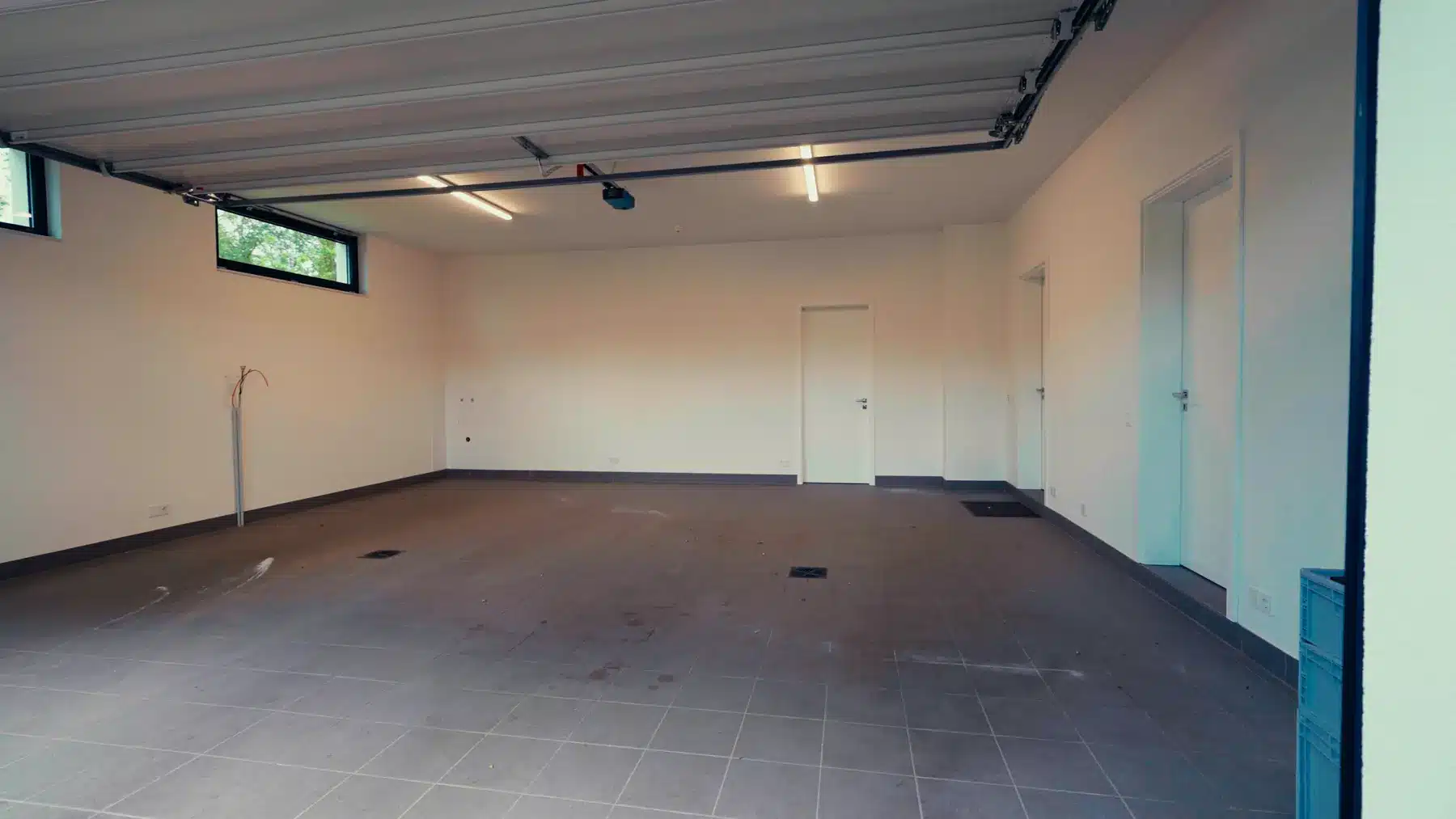 Sportwagen-Garage vorher: leerer Raum mit grauem Fliesenboden