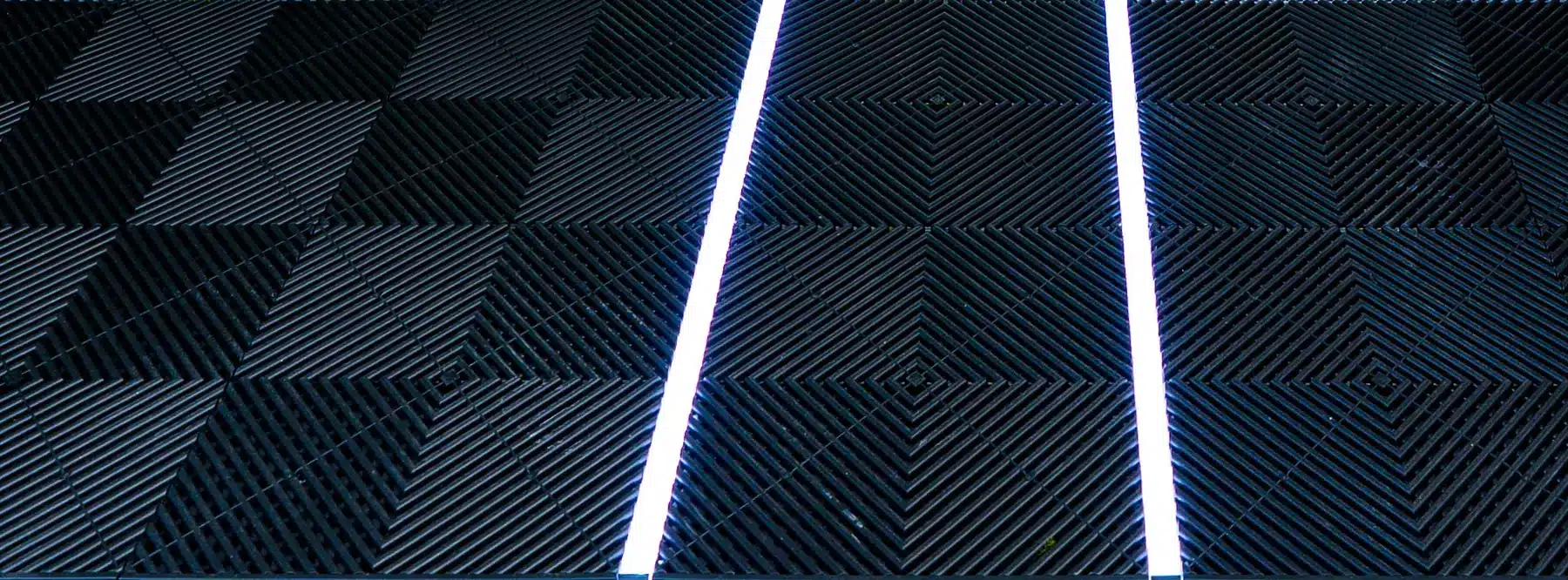 Fahrgasse aus schwarzen Klickfliesen zwischen zwei weißen LED-Lichtleisten