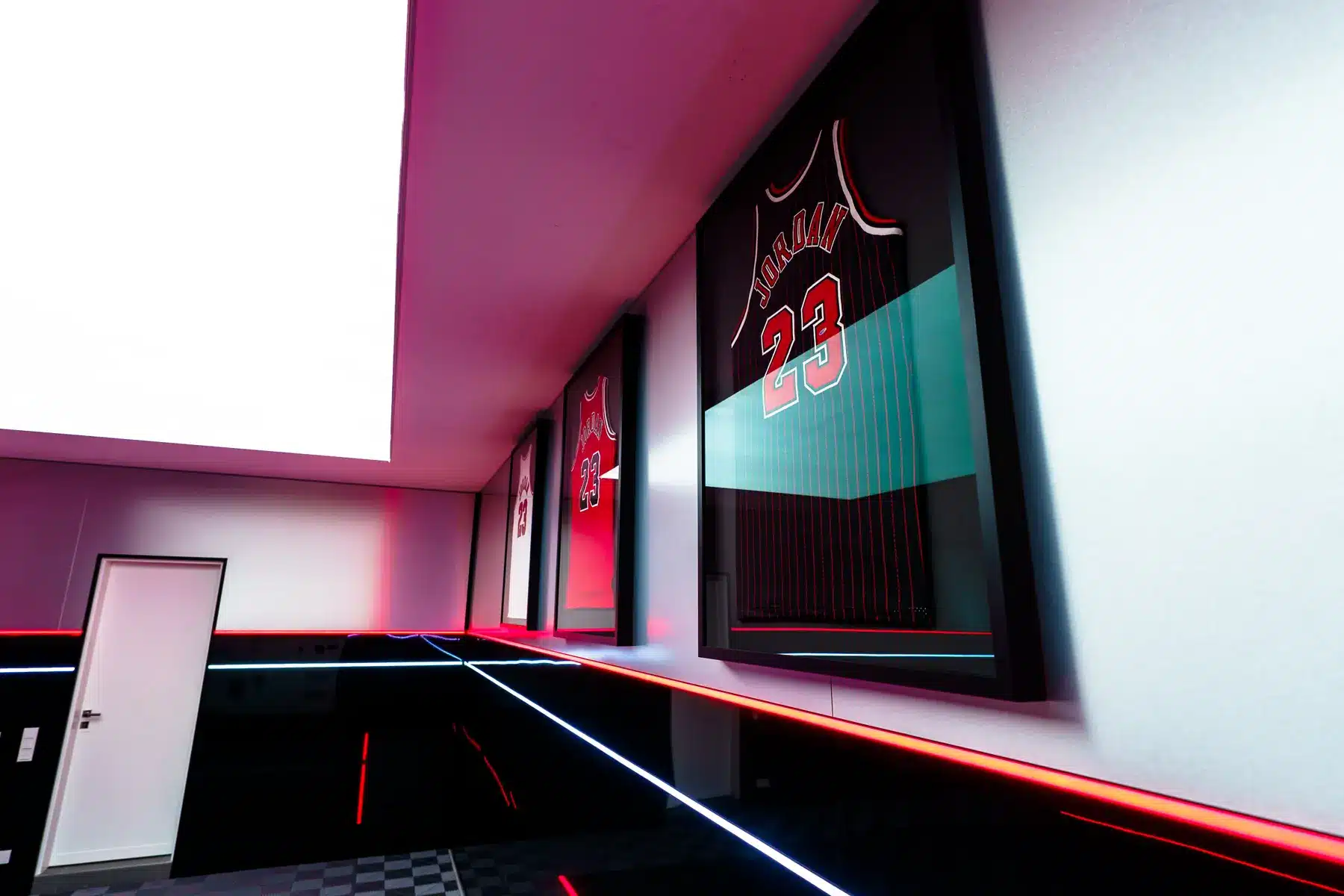 Daily-Garage: gerahmte Trikots über Alu-Dibond-Wand mit roter LED-Linie